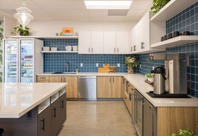 Sleek kitchen area with blue tiled backsplash, wooden cabinetry, and coffee station.
