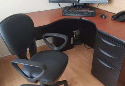 Private workstation with an L-shaped desk, dual monitors, and a black ergonomic task chair.