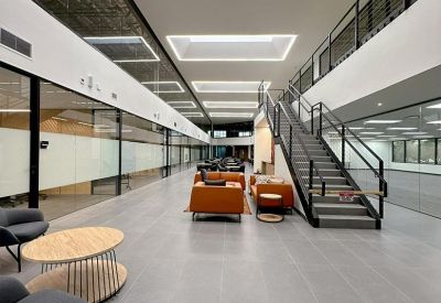 Expansive communal atrium with a central staircase, lounge seating, and skylights.