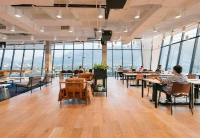 Open-plan coworking space with large windows overlooking city mountains.