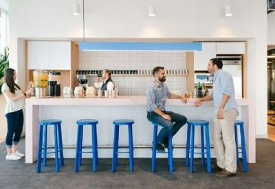 Modern office pantry and bar area with blue stools and white counter.