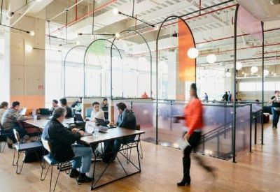 Bright multi-level breakout area with glass partitions and arched metal frames.