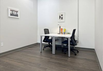 Internal two-person office suite with white desks and framed wall art.