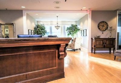 Elegant wood-paneled reception desk with a view into a sunlit lounge area.