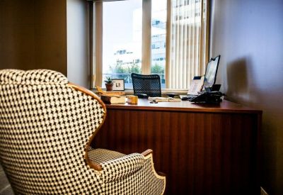 Private office with a patterned wingback chair and large window overlooking the city.