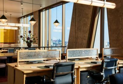 Row of wooden desks with modern task chairs and city views.