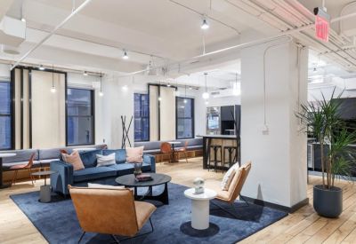 Spacious communal lounge with a blue velvet sofa, tan leather armchairs, and wood floors.