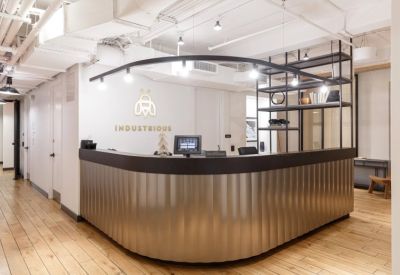 Modern reception desk with a corrugated metallic base and gold Industrious logo.