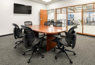 Professional conference room with a large wood-finish table and black ergonomic mesh chairs.