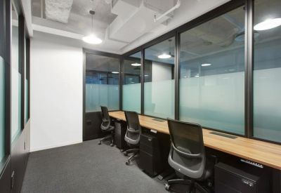 Private office suite with a long wooden desk, black chairs, and frosted glass partitions.