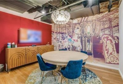 Meeting room featuring a round table, blue velvet chairs, and a whimsical carousel wall mural.