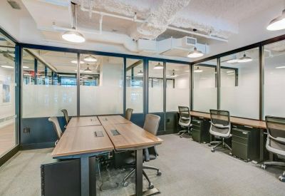 Internal office space with multiple workstations and exposed industrial ceiling pipes.