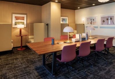Long wooden library table with warm desk lamps and plush privacy booths.