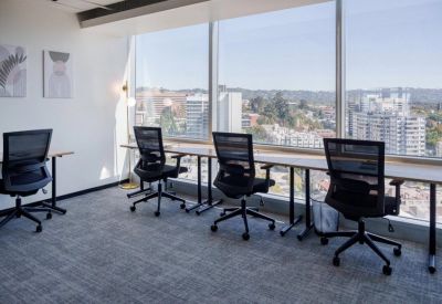 Modern workspace with ergonomic mesh chairs facing a large window with city views.