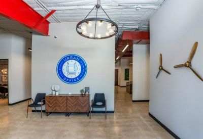 Reception area with a branded blue logo, chevron-patterned credenza, and mid-century modern chairs.