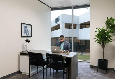 Bright private office suite with a desk, black chairs, and a large window.