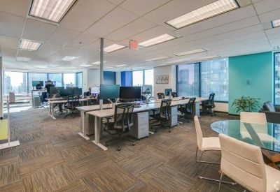 Modern open-plan office with multiple rows of desks and ergonomic chairs.