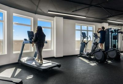 Fitness center featuring treadmills and elliptical machines with large windows.