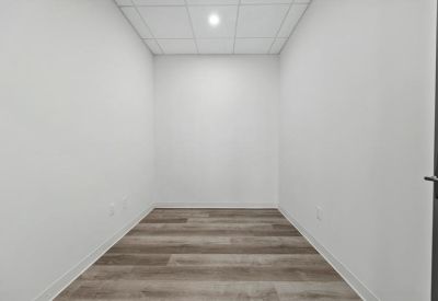 Bright, empty private office with light wood flooring and white walls.