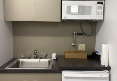 Compact breakroom area with brown cabinetry and essential appliances.