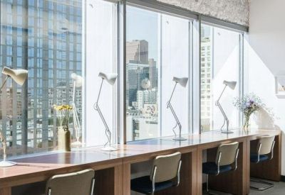 Sunlit window-side workstations with individual desk lamps and wooden finishes.