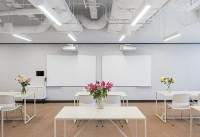 Bright training room with white tables, floral arrangements, and dual whiteboards.