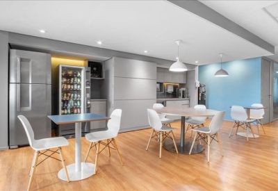 Modern kitchen and dining area with stainless steel fridge, vending machine, and white chairs.