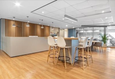 Reception area with a light grey front desk and high-top seating for guests.