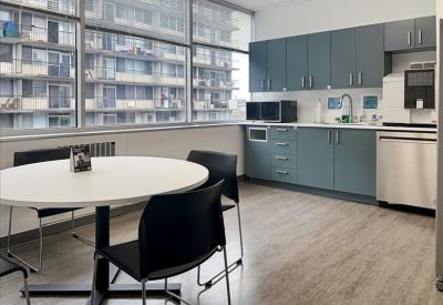 Modern communal kitchen and break area with blue cabinetry and large windows.