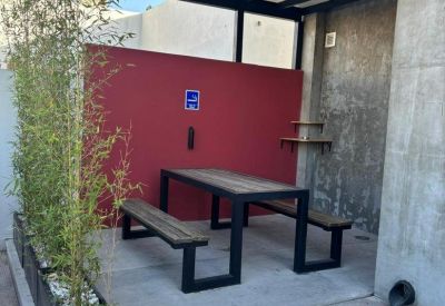 Covered outdoor communal break area with wooden picnic tables and bamboo privacy plants.