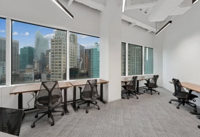 Modern open-plan office with timber floors, city views, and a lounge area with a pink sofa.