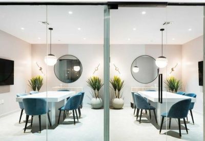 Professional meeting room with two white tables, blue velvet chairs, and round mirrors.