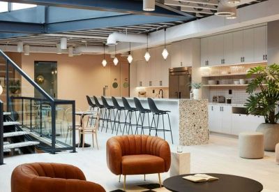 Bright modern kitchen and cafe area with leather armchairs and a patterned stone island.