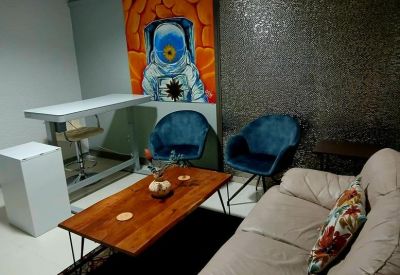 Relaxation corner with blue velvet chairs, a wooden coffee table, and astronaut mural.
