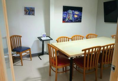 Bright meeting room with a light wood table and orange-cushioned chairs.