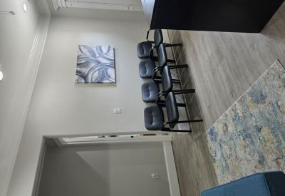 Waiting area with a row of black chairs and blue-toned abstract art.