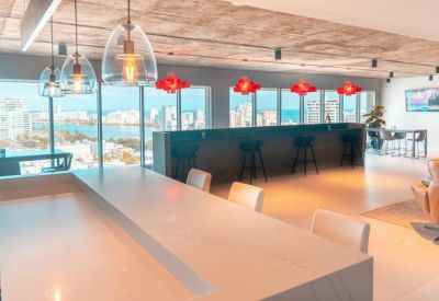 Bright coworking area with a long breakfast bar and glass pendant lights overlooking the city.
