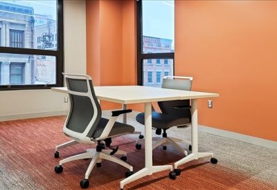 Private office featuring an orange accent wall and two workstations with street views.