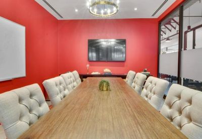 Bright meeting room with red walls, a long wooden table, and white tufted chairs.