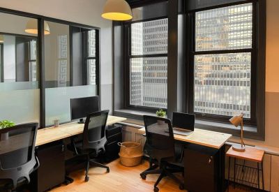 Bright private office with wood desks and large windows overlooking the city.