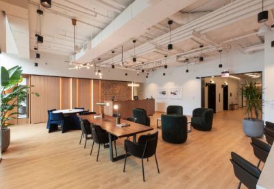 Lounge and reception area featuring mid-century modern furniture, a long wooden desk, and green plants.