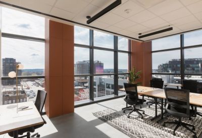 Open office area with individual desks, ergonomic chairs, and large windows overlooking the city.