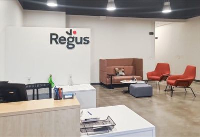 Modern reception area with branded Regus signage and a colorful breakout seating area.