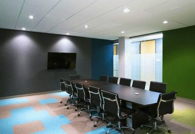 Modern conference room with a long dark table, black ergonomic chairs, and a colorful patterned carpet.