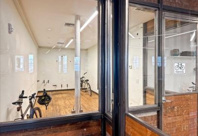 Glass-walled indoor bicycle storage room with wooden floors.