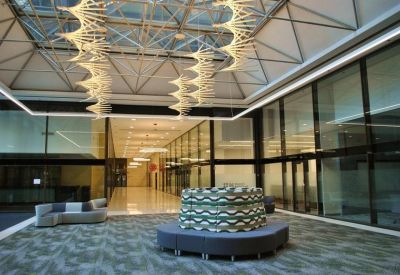 Spacious lobby with a glass ceiling, unique spiral light fixtures, and a circular bench.