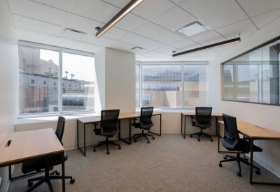 Shared office space with multiple workstations and large windows overlooking the city.