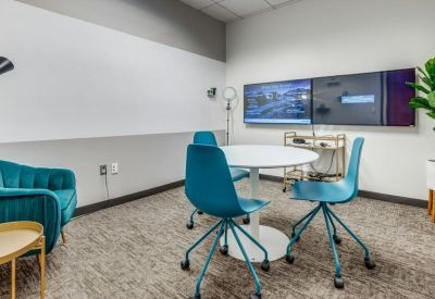 Small collaborative space with teal chairs and a white circular table.