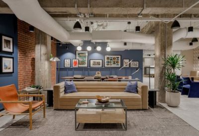 Stylish lounge area with a tan sofa, blue pillows, and brick accent wall.
