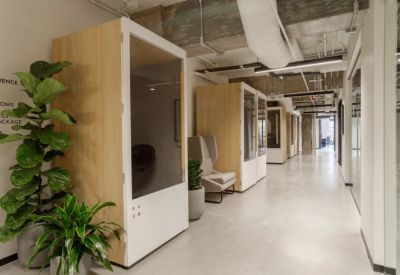 Bright corridor lined with private soundproof phone booths and indoor plants.